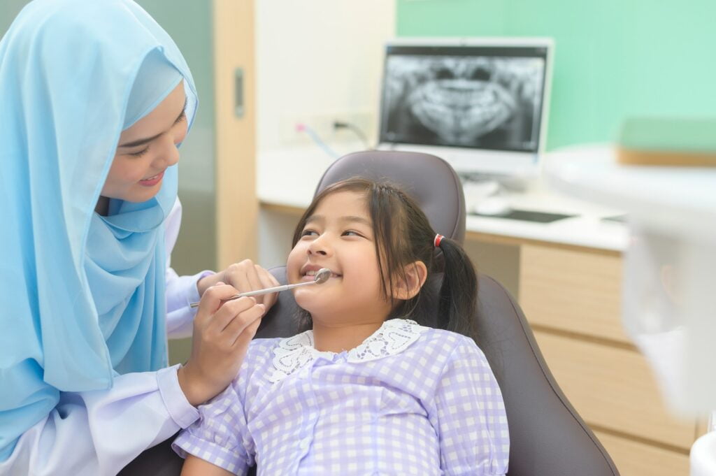 A little cute girl having teeth examined by muslim dentist in dental clinic, teeth check-up at Klinik Pergigian ADL, Petaling Jaya Dental Clinic